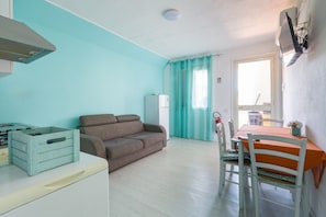 Une pièce comprenant un coin cuisine, un canapé, une table à manger avec des chaises et une fenêtre avec des rideaux.