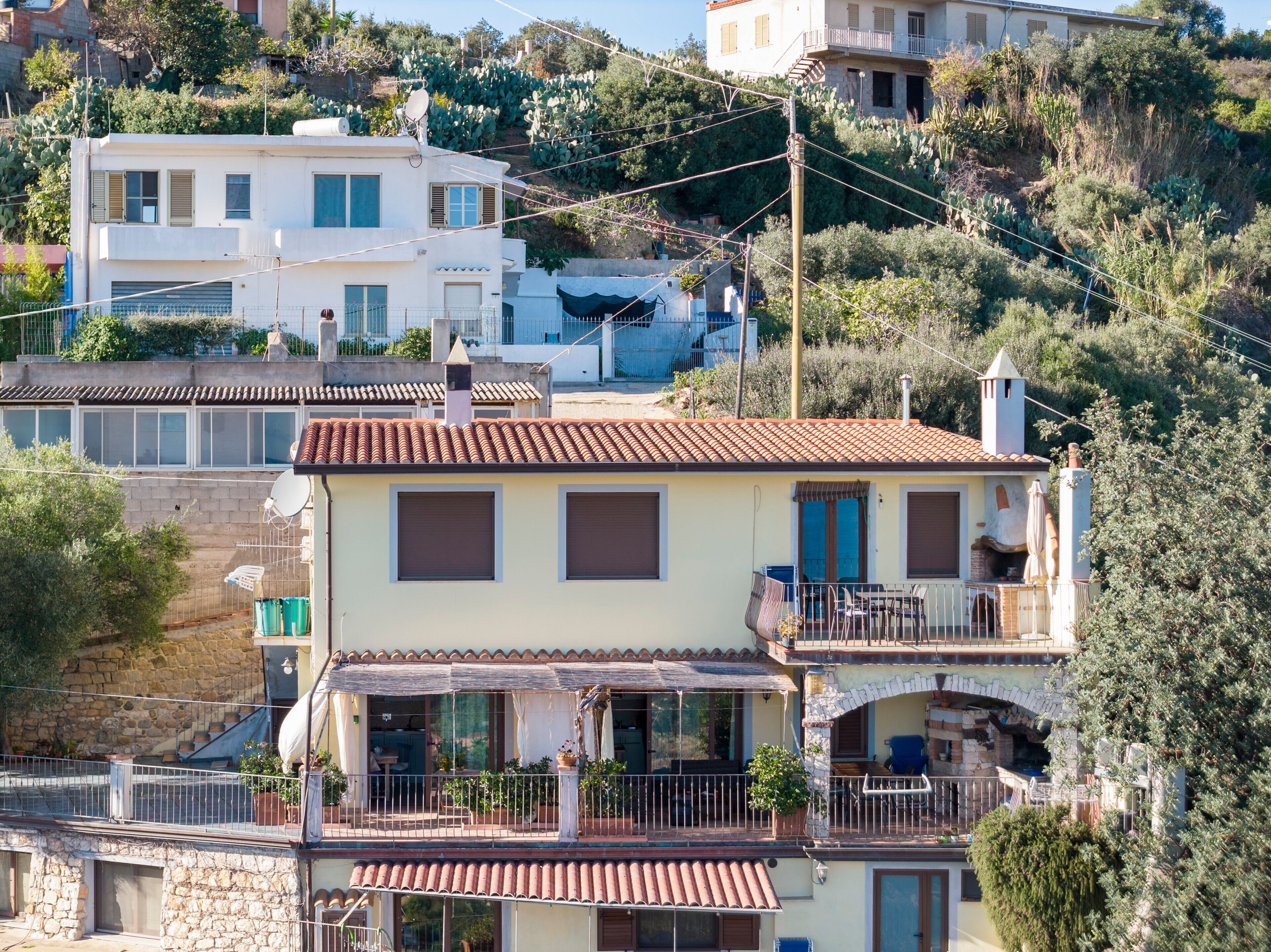 Un edificio de varios pisos con balcones, una terraza y vistas a una colina.