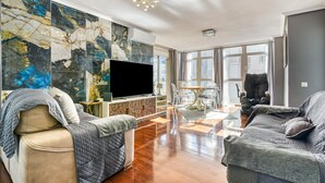 A living room with a large TV, a sofa, a chair, a coffee table, and a wall with a marble-like design. - Apartment 'Altea Beach' with Sea View, Wi-Fi and Air Conditioning (Altea)