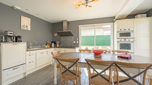 Une cuisine avec des armoires blanches, une table à manger en bois et un luminaire moderne.