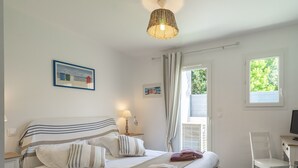 Une chambre à coucher avec un lit, une table de chevet, une lampe et une vue sur l’extérieur.