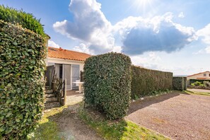 A residential property with a gravel driveway, a neatly trimmed hedge, and a house with a red-tiled roof. - Le Phare - Holiday Home with Shared Pool and Private Garden - PO26 (Pornic)