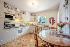 A kitchen with white cabinets, a microwave, a stove, and a dining table with chairs.
