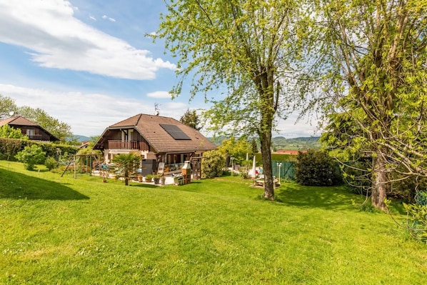 A house with a sloped roof, a patio, and a garden.