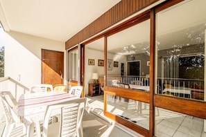 Une pièce comprenant une table à manger, des chaises, une porte en bois et une porte-fenêtre coulissante donnant sur un espace extérieur.
