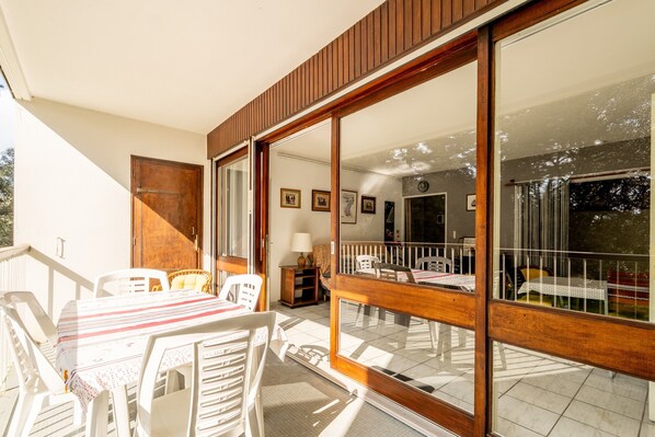 A room with a dining table, chairs, a wooden door, and a sliding glass door leading to an outdoor area.