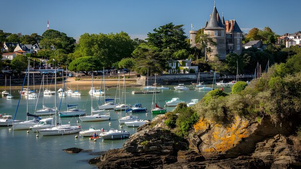 A coastal town with a historic tower, marina with boats, and lush greenery. - At Aux Pins Maritimes, with Beautiful Terrace - A22 (Pornic)