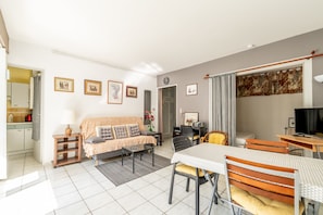 Une pièce bien éclairée, avec un canapé, une table à manger, des chaises et un téléviseur.
