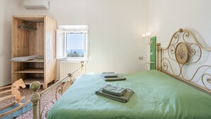 Un dormitorio con cama, armario de madera, radiador, ventana y candelabro.