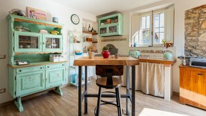 Una cocina con una mesa de madera, un armario verde y una pared de piedra.