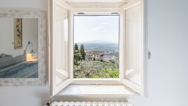 An open window with a view of a building and trees.