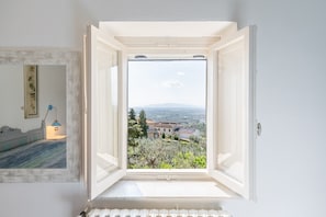 Ventana abierta con vista a un edificio y árboles.