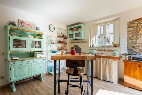 Una cocina con una mesa de madera, un armario verde y una pared de piedra.