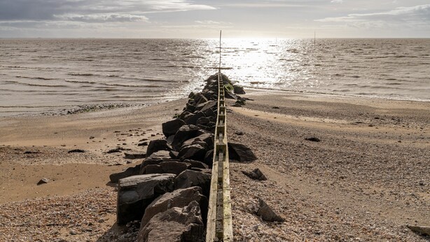 Un muelle de madera que se adentra en el mar bajo un cielo despejado.