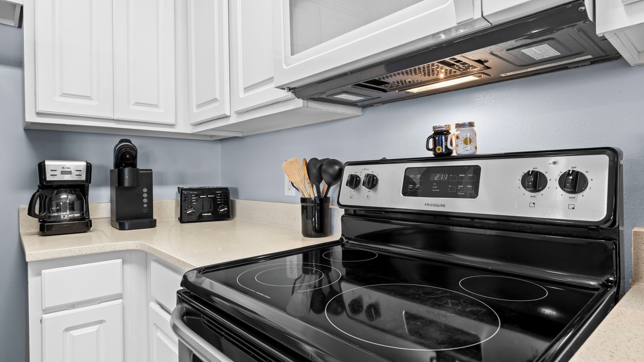 A kitchen with a black stove, a coffee maker, a toaster, and a microwave.