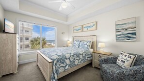 A bedroom with a bed, bedside tables, a nightstand, a dresser, and artwork on the walls. - Palm Beach B31 Gulf Front 3BR 2BA Corner Unit (Orange Beach)