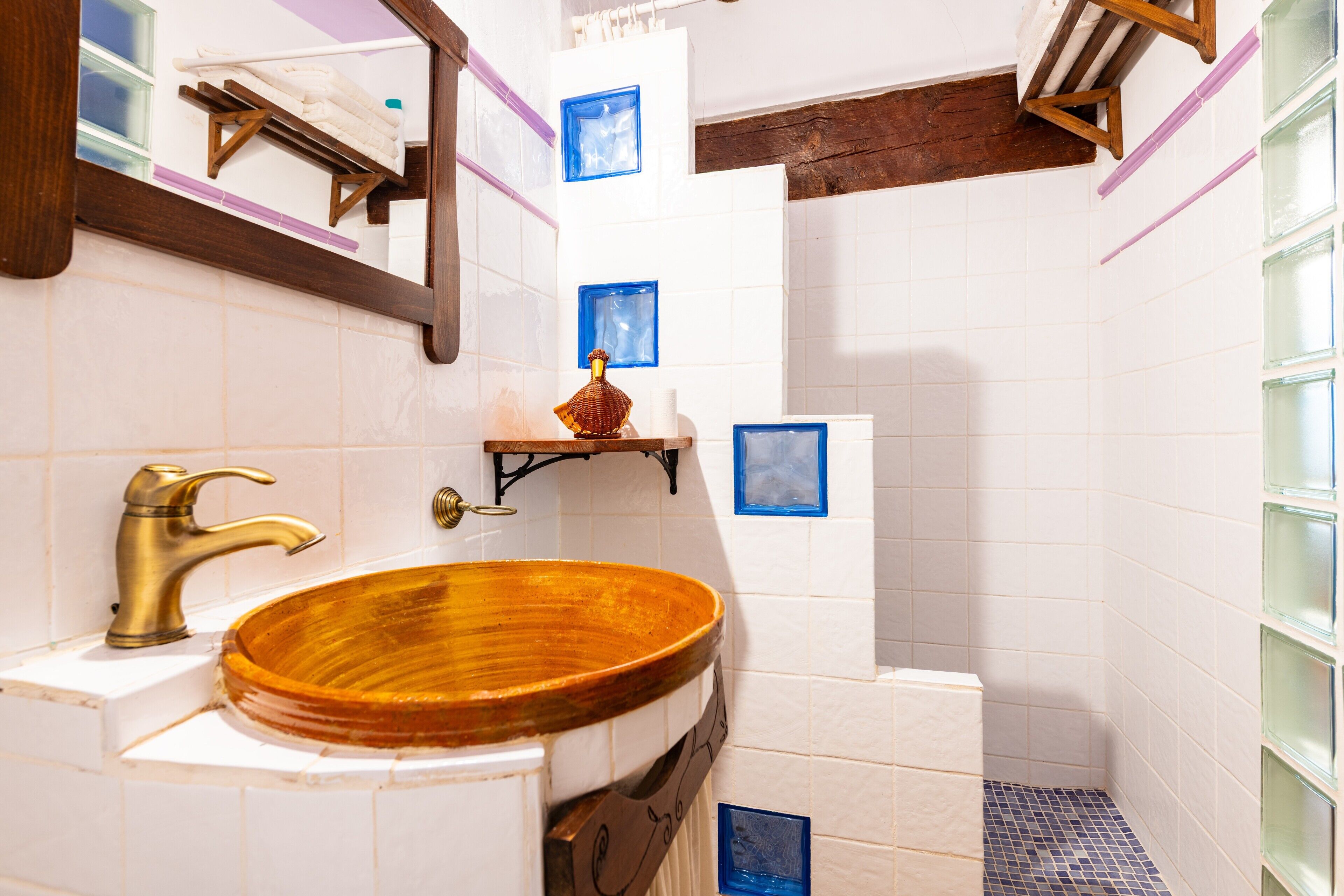 A bathroom with a wooden sink, a mirror, and a shelf with a decorative item.
