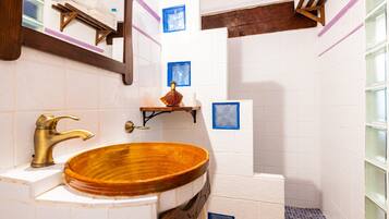 A bathroom with a wooden sink, a mirror, and a shelf with a decorative item.