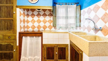 A bathroom with a sink, mirror, and a clock on the wall.