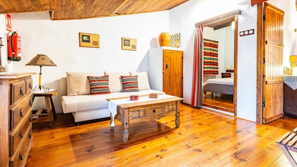 Une pièce chaleureuse avec un plafond en bois, un canapé blanc orné de coussins à rayures, une table basse en bois et un meuble en bois.