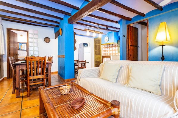 A cozy room with a wooden dining table, a sofa, and a lamp.