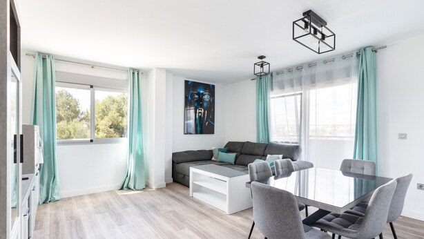 Una sala de estar moderna con un sofá, una mesa de centro de vidrio y una mesa de comedor con sillas.