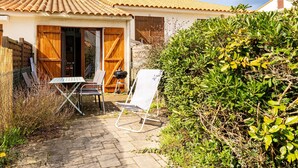 A patio with a table and chairs, a wooden fence, and a house with a tiled roof. - Le Petit Voilier 'Family Spirit & Ocean' with Private Pool and Garden, PO30 (Pornic)