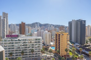A hotel with multiple floors, a pool area, and a view of the cityscape.
