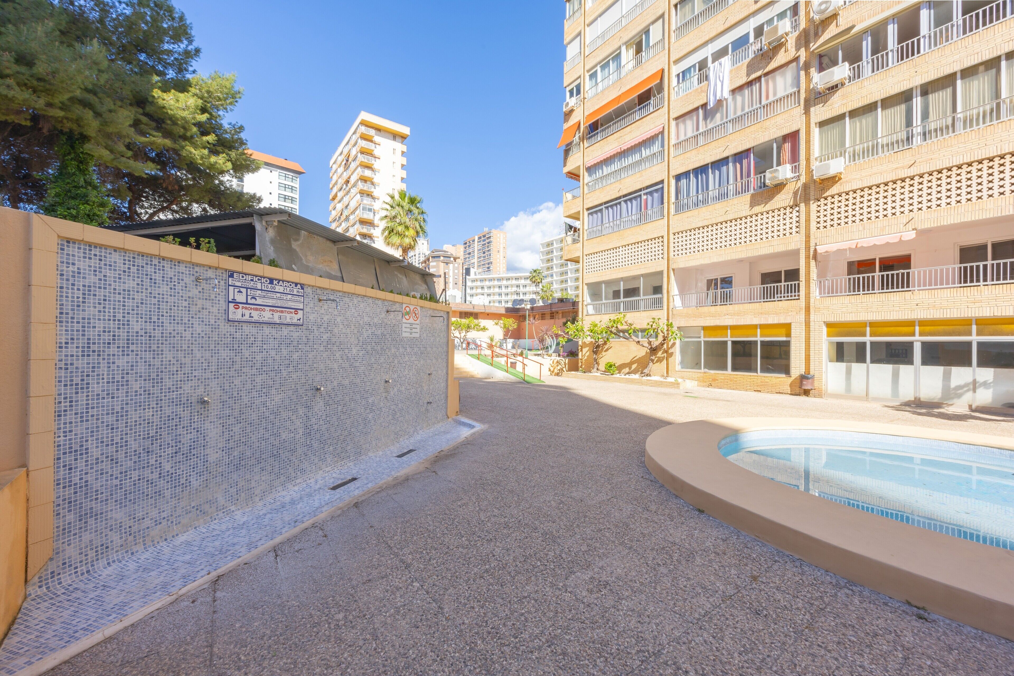 A swimming pool area with a tiled wall and a sign indicating a building named 'Edificio Karola.'