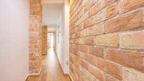 A hallway with brick walls and wooden flooring, leading to a room with a door at the end. - Apartment 'Poniente' with Balcony, Wi-Fi and Air Conditioning (Benidorm)