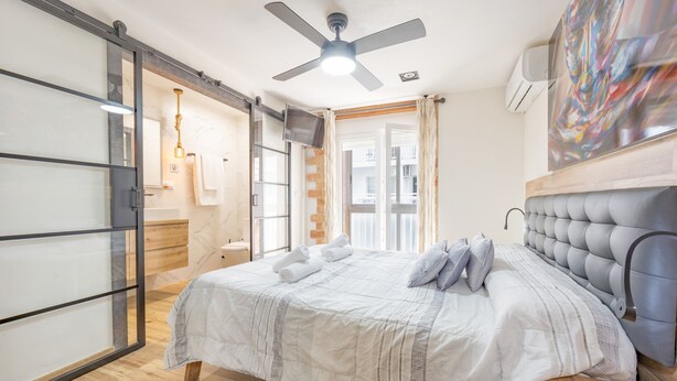 A bedroom with a bed, a ceiling fan, a sliding glass door, and a painting on the wall. - Apartment 'Poniente' with Balcony, Wi-Fi and Air Conditioning (Benidorm)