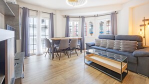 A modern living room with a sofa, a coffee table, a dining table with chairs, and large windows with curtains. - Apartment 'Poniente' with Balcony, Wi-Fi and Air Conditioning (Benidorm)