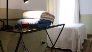 Una habitación con cama, una mesa con lámpara y una ventana con cortinas.