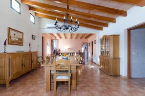 Un comedor con una mesa y sillas de madera, una araña y un aparador.