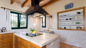 A kitchen with wooden cabinets, a built-in stove, a black range hood, and a window with green frames. - Villa 'Viñas Ref 259' with Mountain Views, Private Pool and Wi-Fi (Son Servera)