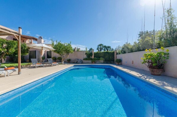 Una piscina con tumbonas, una pérgola y plantas en macetas.