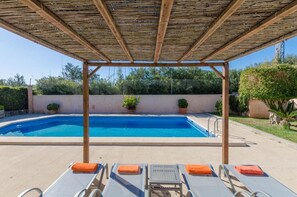 A swimming pool with lounge chairs and a pergola overhead.