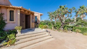 A house with a stone staircase leading to a wooden door, surrounded by lush greenery and palm trees. - Villa 'Viñas Ref 259' with Mountain Views, Private Pool and Wi-Fi (Son Servera)