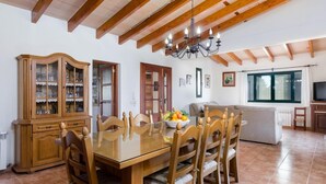 A dining area with a wooden table and chairs, a chandelier, and a cabinet with glass doors. - Villa 'Viñas Ref 259' with Mountain Views, Private Pool and Wi-Fi (Son Servera)