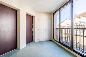 A room with a large window, a door, and a carpeted floor.