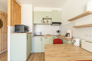 A compact kitchen with a microwave, coffee maker, and a red chair. - Studio 'A011 - Old Port View Pornic' with Wi-Fi (Pornic)