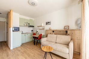 A modern kitchen with a dining area, a sofa, and a small round table.