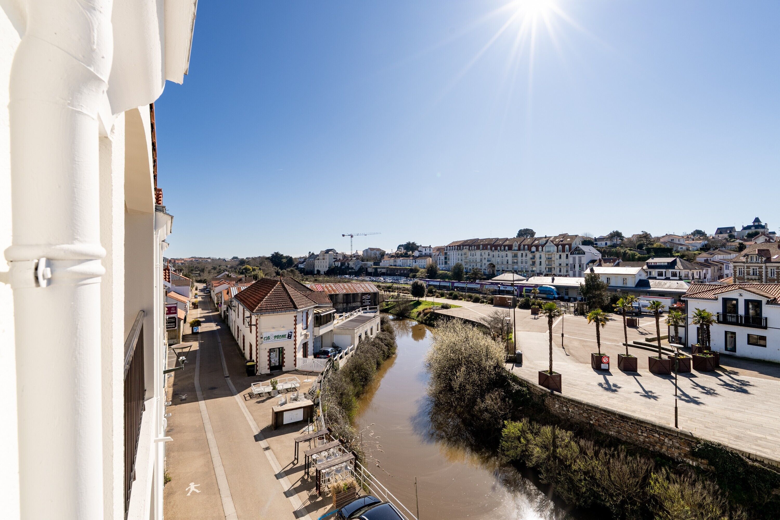Une vue sur une ville au bord de la rivière, avec ses bâtiments, un pont et un ciel dégagé.