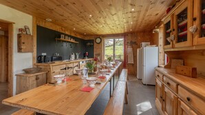 A wooden interior with a long dining table, kitchen area, and wooden cabinets. - Discover Gîte Le Pradel in Les Estables
 (Les Estables)