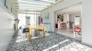 A modern kitchen with a dining area, featuring a large window, a patterned floor, and a ceiling with skylights. - Holiday Home Le Havre du Capitaine with Private Terrace and Wi-Fi (19) (Pornic)