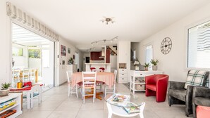 A spacious living area with a dining table, red and grey sofas, and a kitchen in the background. - Holiday Home Le Havre du Capitaine with Private Terrace and Wi-Fi (19) (Pornic)