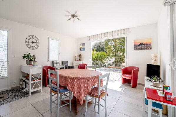 Un espace repas comprenant une table ronde, des chaises, un ventilateur de plafond et une vue sur l’extérieur.