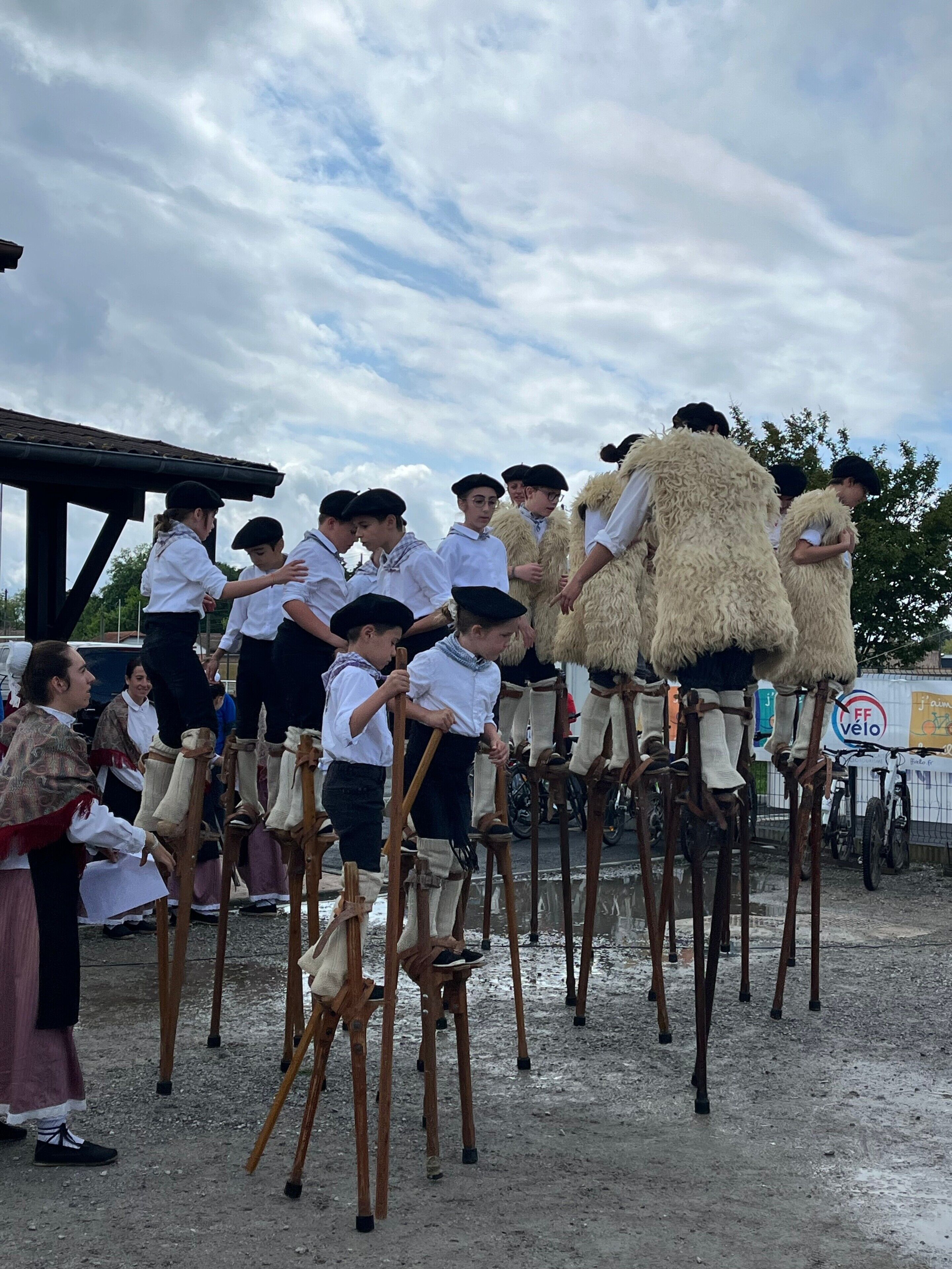 Un grupo de personas vestidas con atuendos tradicionales sobre pilotes en un espacio abierto.