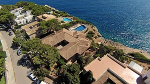 An aerial view of a coastal property with a swimming pool, multiple buildings, and a road. - Country House 'Ses Penyes' with Sea View, Wi-Fi and Air Conditioning (Santanyí)