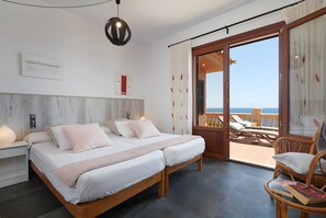 Ein Schlafzimmer mit Bett, Nachttischen, einem Lesesessel und einem Balkon mit Blick.